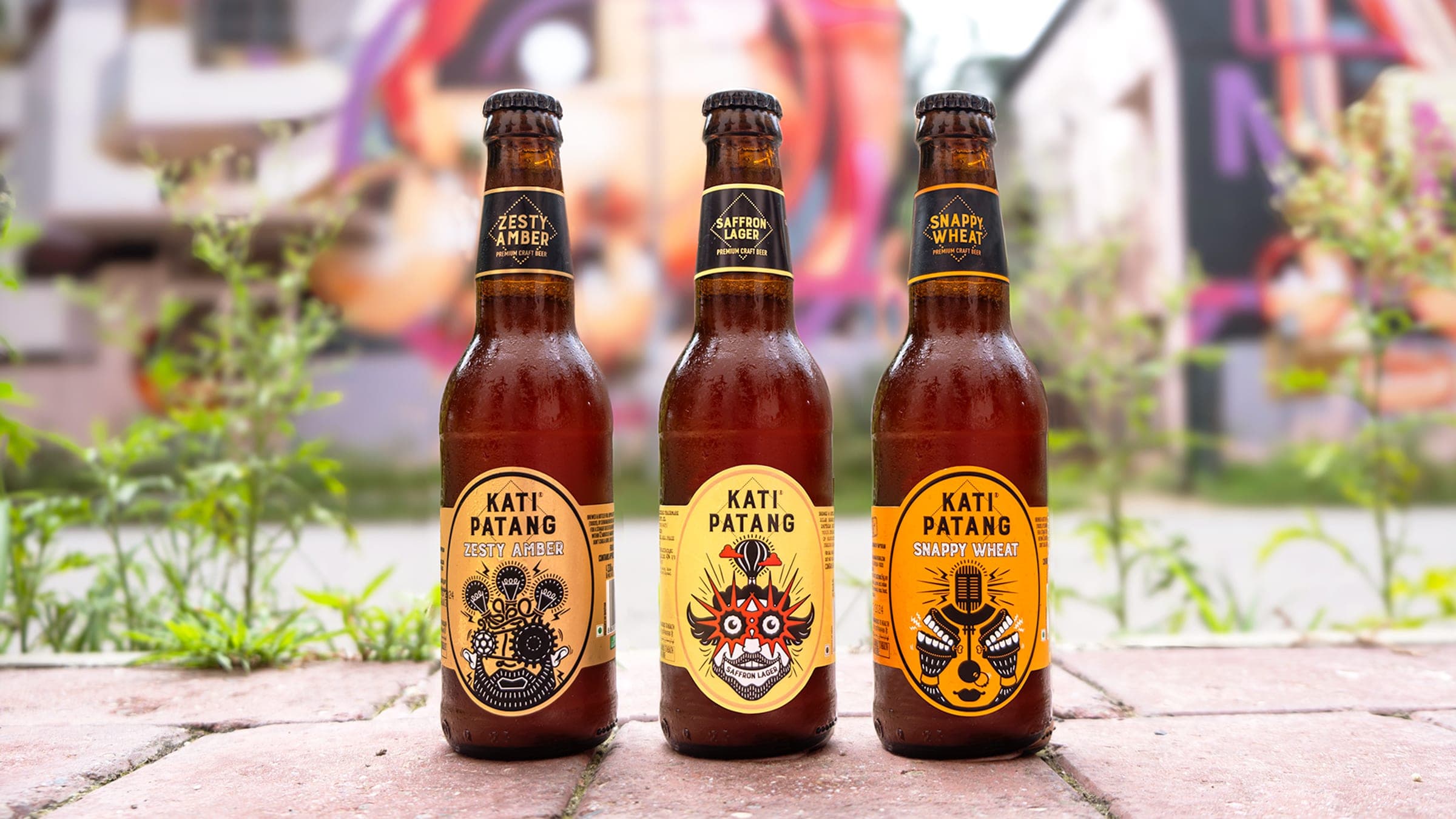 Zesty Amber, Saffron Lager and Snappy Wheat bottles lined up against a painted wall